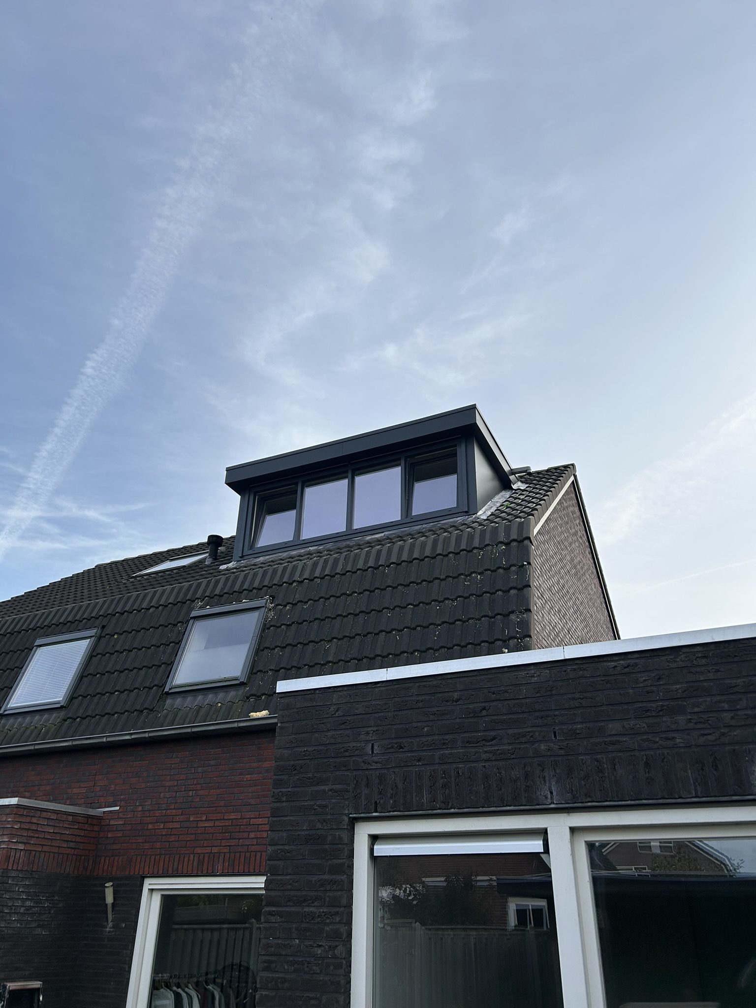 Vakkundig geplaatste antraciet dakkapel op maat met houtnerf kozijnen en weggewerkt rolluik door C.H. Montage.